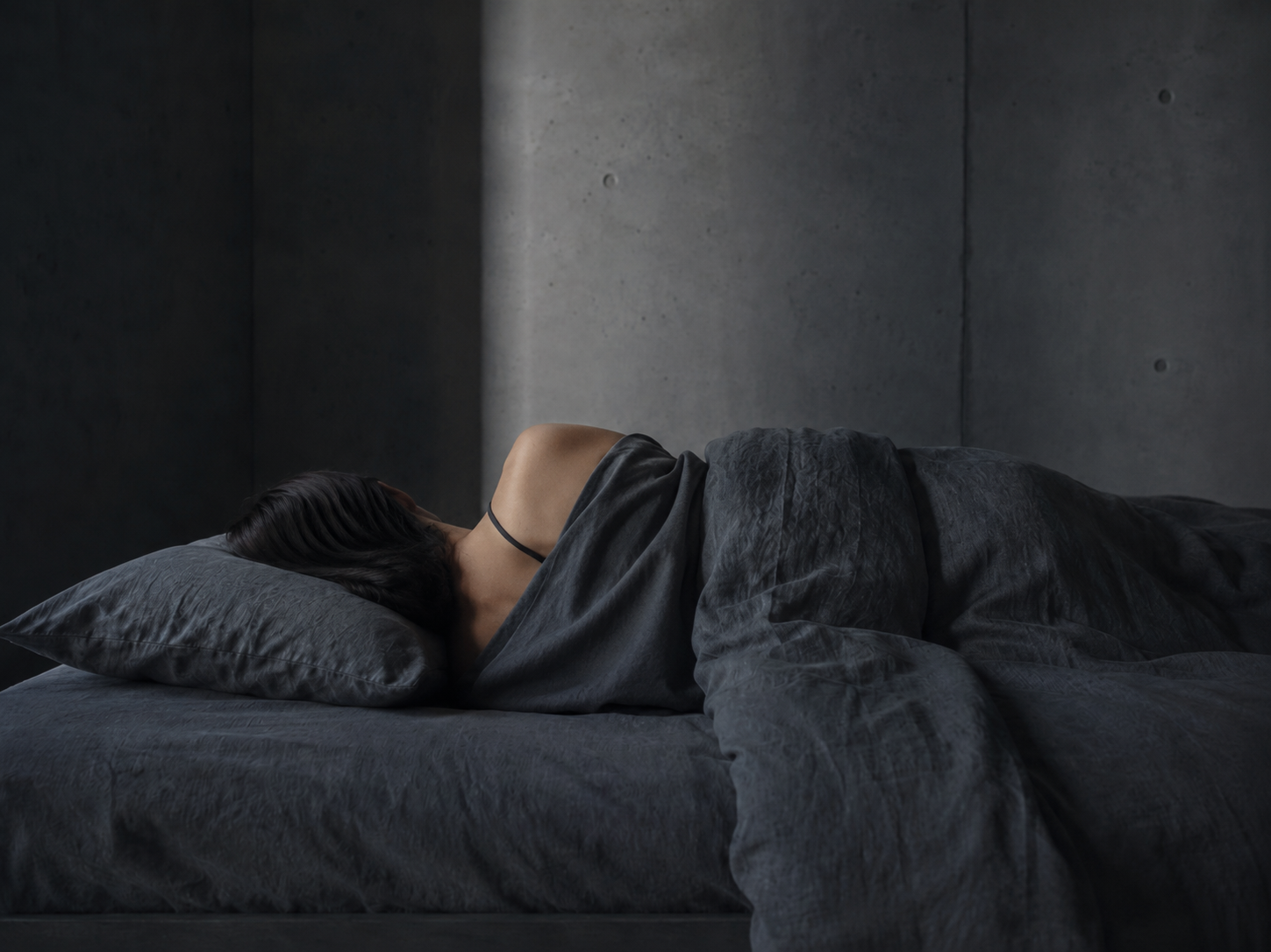 Person sleeping in dark charcoal linen bed