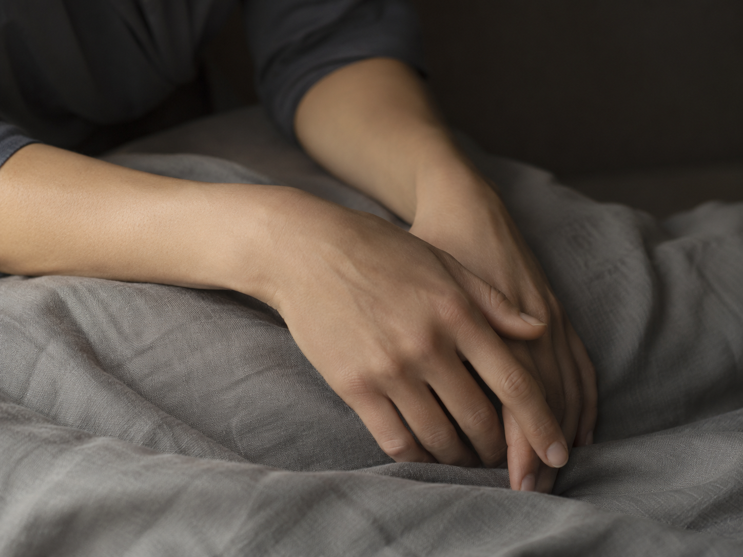 Hands resting on dark linen fabric