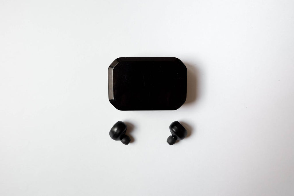 Black wireless earbuds with charging case flat-lay on white background