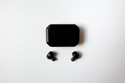 Black wireless earbuds with charging case flat-lay on white background